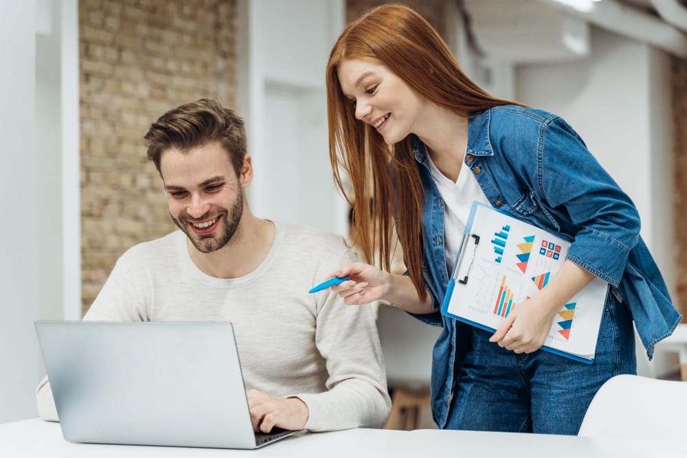 A man and woman engage with a laptop, focusing on SEO strategies for their agency.